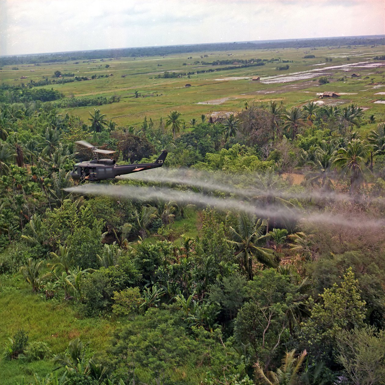 Śmigłowiec UH-1D z 336th Aviation Company rozpyla środek do defoliacji na gęstym obszarze dżungli w delcie Mekongu, 26 lipca 1969 autorstwa American Photographer