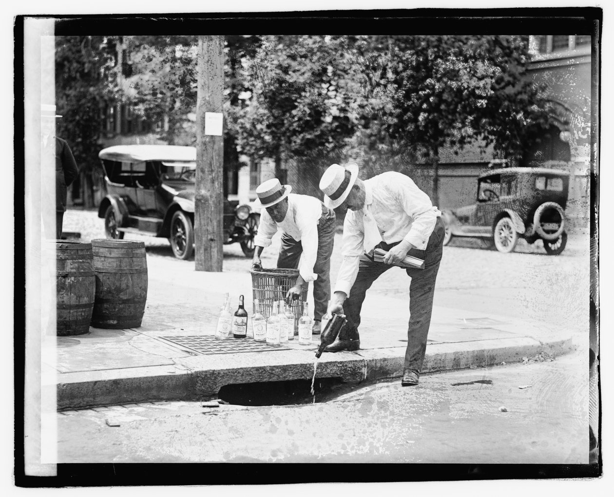 Dwóch mężczyzn nalewających alkohol do kanalizacji deszczowej, 8 lipca 1921 (zdjęcie czarno-białe) autorstwa American Photographer