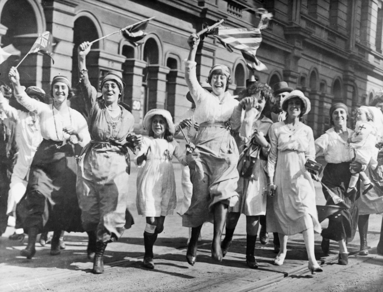 Grupa kobiet i dzieci radujących się na ulicy w Sydney podczas podpisania rozejmu, 11 listopada 1918 autorstwa Australian Photographer