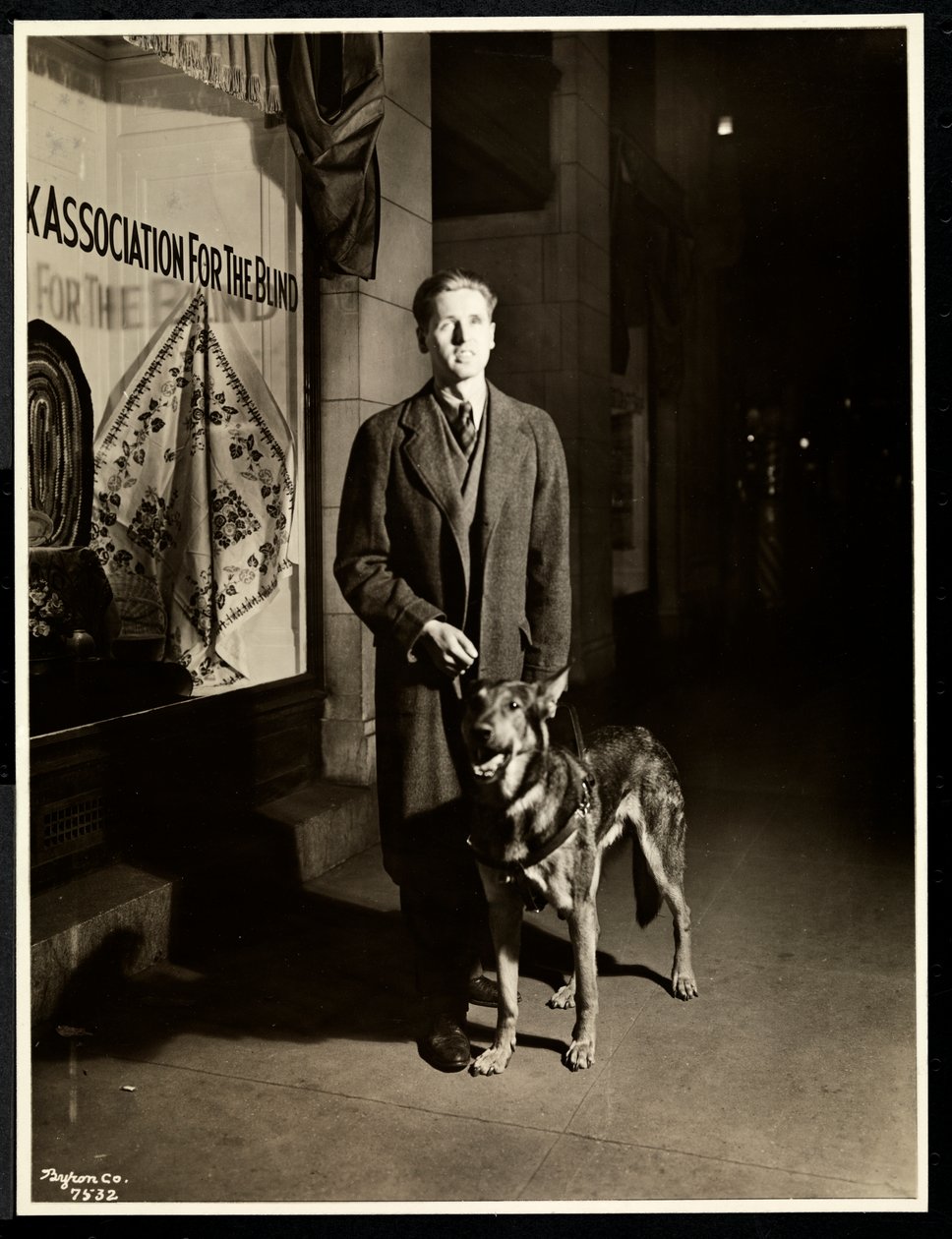 Ślepiec i jego pies przewodnik na chodniku przed nowojorskim Stowarzyszeniem dla Niewidomych, 111 East 59th Street, Nowy Jork, 1938 (srebrny odbitka żelatynowa) autorstwa Byron Company