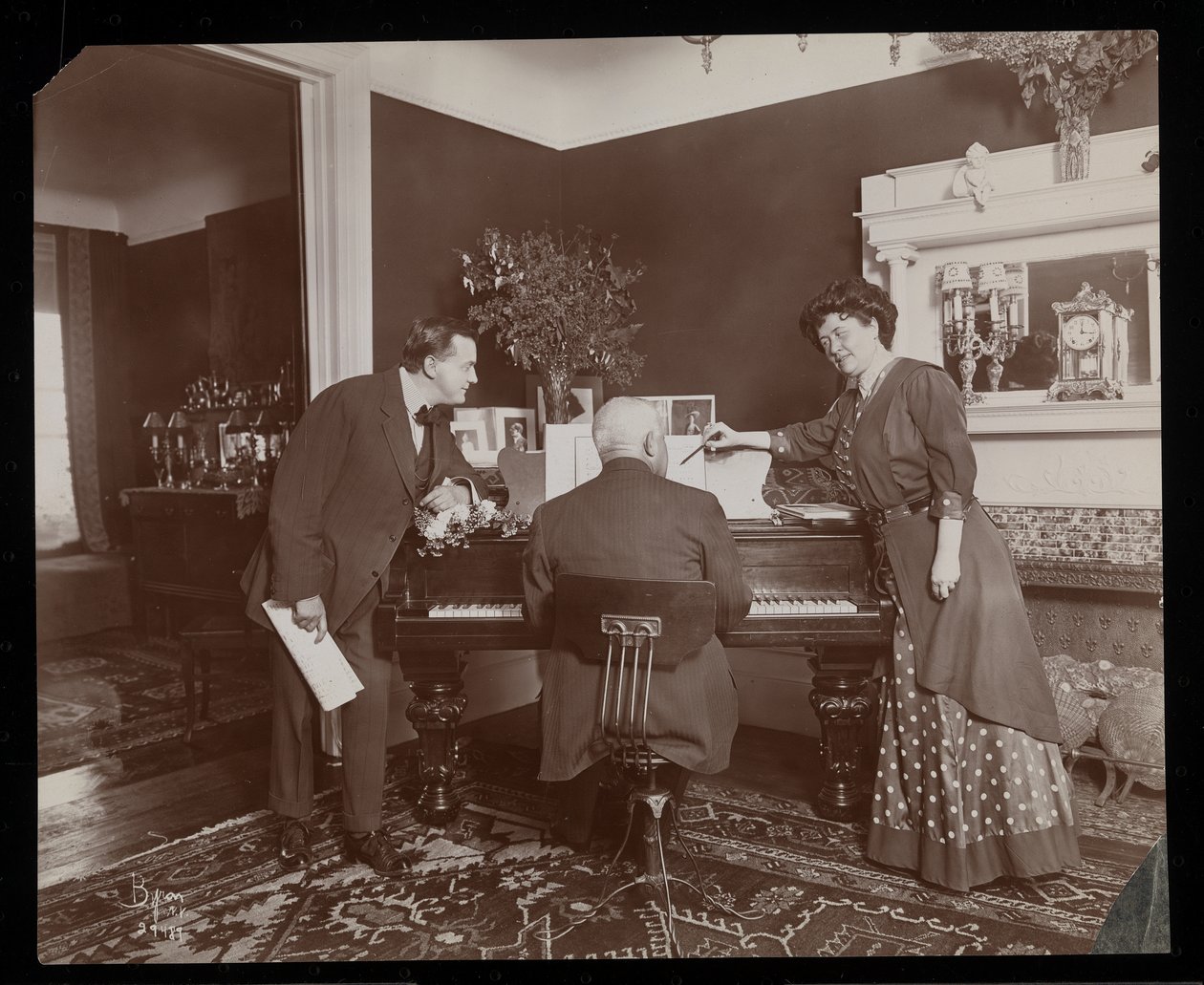Clara De Regand wskazuje partyturę, podczas gdy mężczyzna gra na pianinie, 1910 (srebrny odbitka żelatynowa) autorstwa Byron Company
