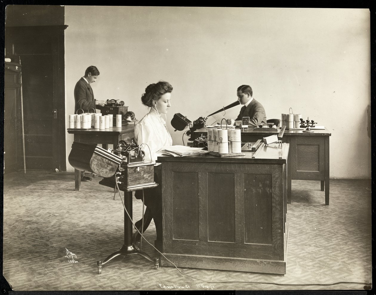 Widok wnętrza kobiety piszącej na maszynie do dyktowania i mężczyzny dyktującego do innej maszyny w Edison Phonograph Co., West Orange, New Jersey, 1903 (odbitka żelatynowa) autorstwa Byron Company