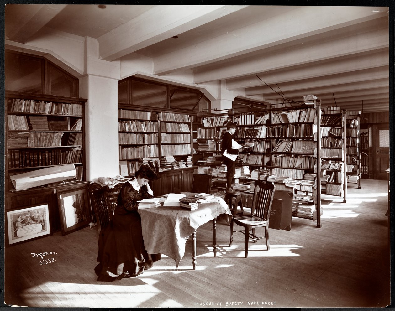 Kobieta i młody mężczyzna w bibliotece Muzeum Urządzeń Bezpieczeństwa Amerykańskiego Instytutu Opieki Społecznej, Nowy Jork, 1907 (srebrny odbitka żelatynowa) autorstwa Byron Company