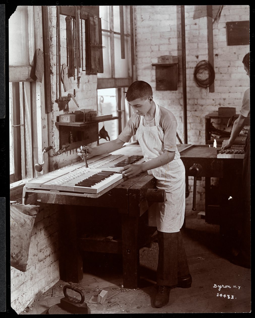 Młody mężczyzna pracujący w fabryce Harrington Piano Co., 1907 (srebrny odbitka żelatynowa) autorstwa Byron Company
