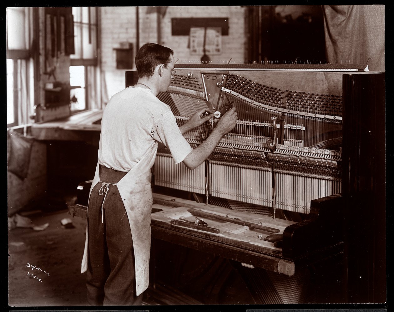 Mężczyzna pracujący w fabryce fortepianów Hardman, Peck und Co., Nowy Jork, 1907 (srebrny odbitka żelatynowa) autorstwa Byron Company