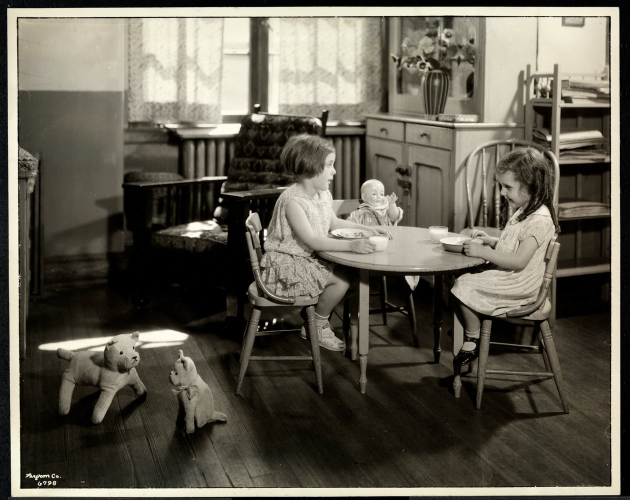 Dwie niewidome, niedowidzące dziewczyny jedzące przy małym stoliku z lalką w nowojorskim stowarzyszeniu dla niewidomych, 111 East 59th Street, Nowy Jork, 1933 (srebrny odbitka żelatynowa) autorstwa Byron Company