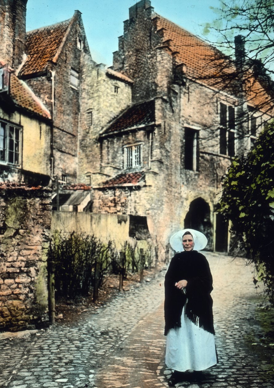 Holandia, prowincja Zeeland. Kobieta przed portalem Kuipers w mieście Middelburg. Data wykonania: około 1920 roku. Archiwum Carla Simona autorstwa Carl Simon
