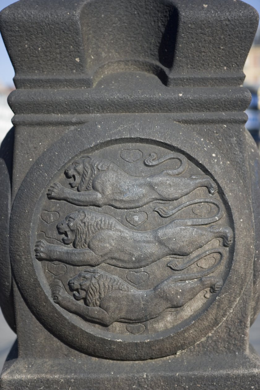 Symbol trzech lwów wyrzeźbiony w kamiennej kolumnie na Placu Ratuszowym autorstwa Danish School