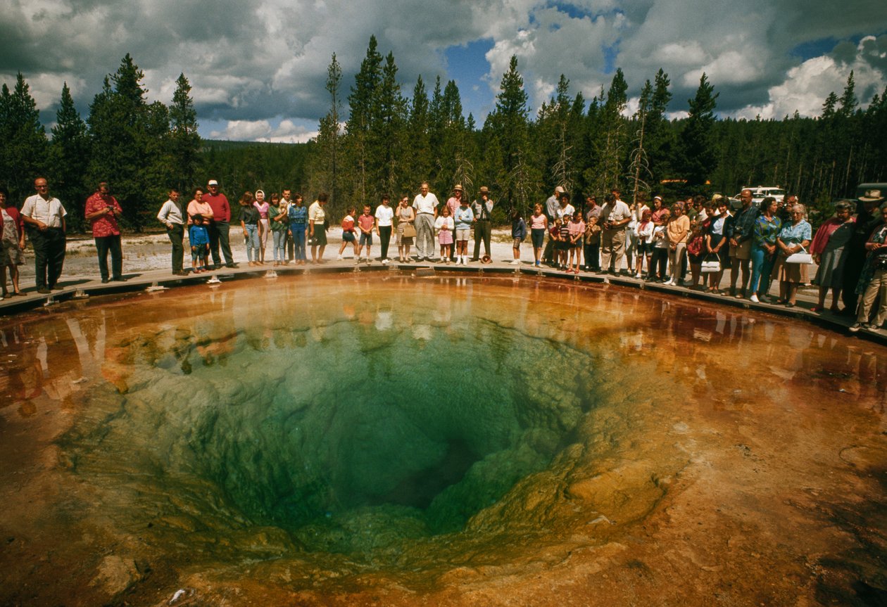 Odwiedzający park gromadzą się wokół niebiesko-zielonego basenu termalnego w kształcie kwiatu. Yellowstone Nati... autorstwa Dean Conger