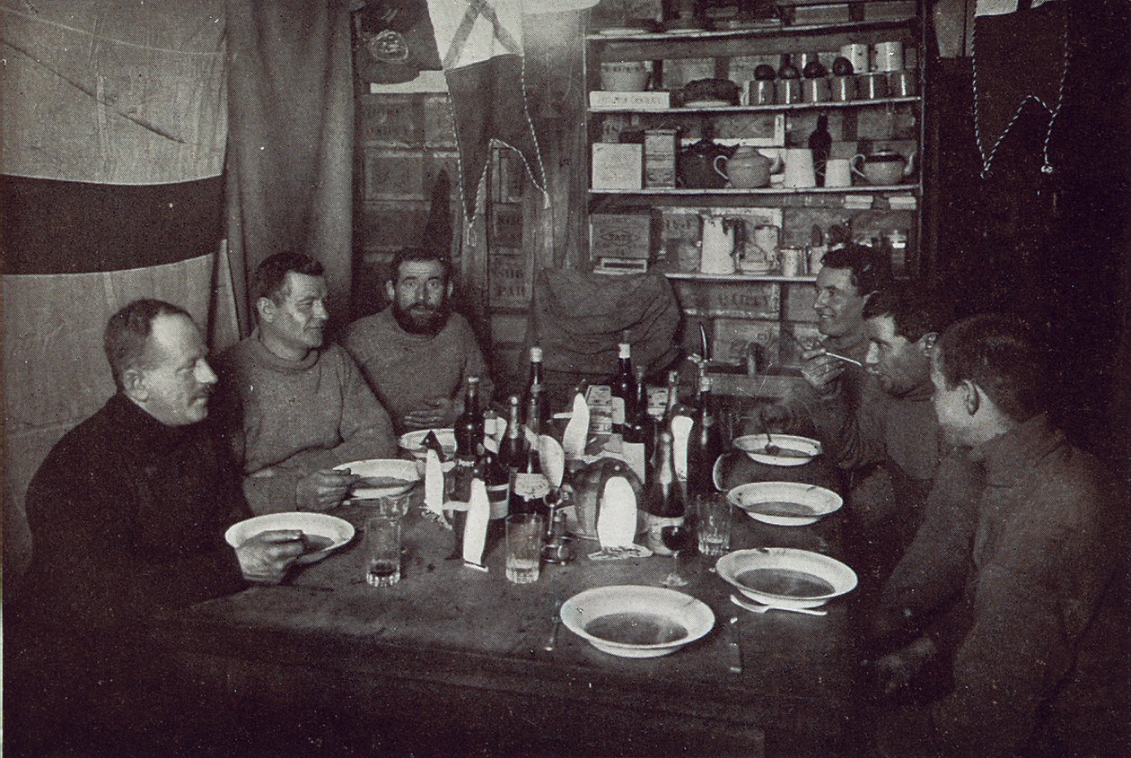 The Men, kolacja z okazji Dnia Środka Zimy, Brytyjska Ekspedycja Antarktyczna, Cape Evans, 22 czerwca 1912 (zdjęcie czarno-białe) autorstwa Edward W. Nelson