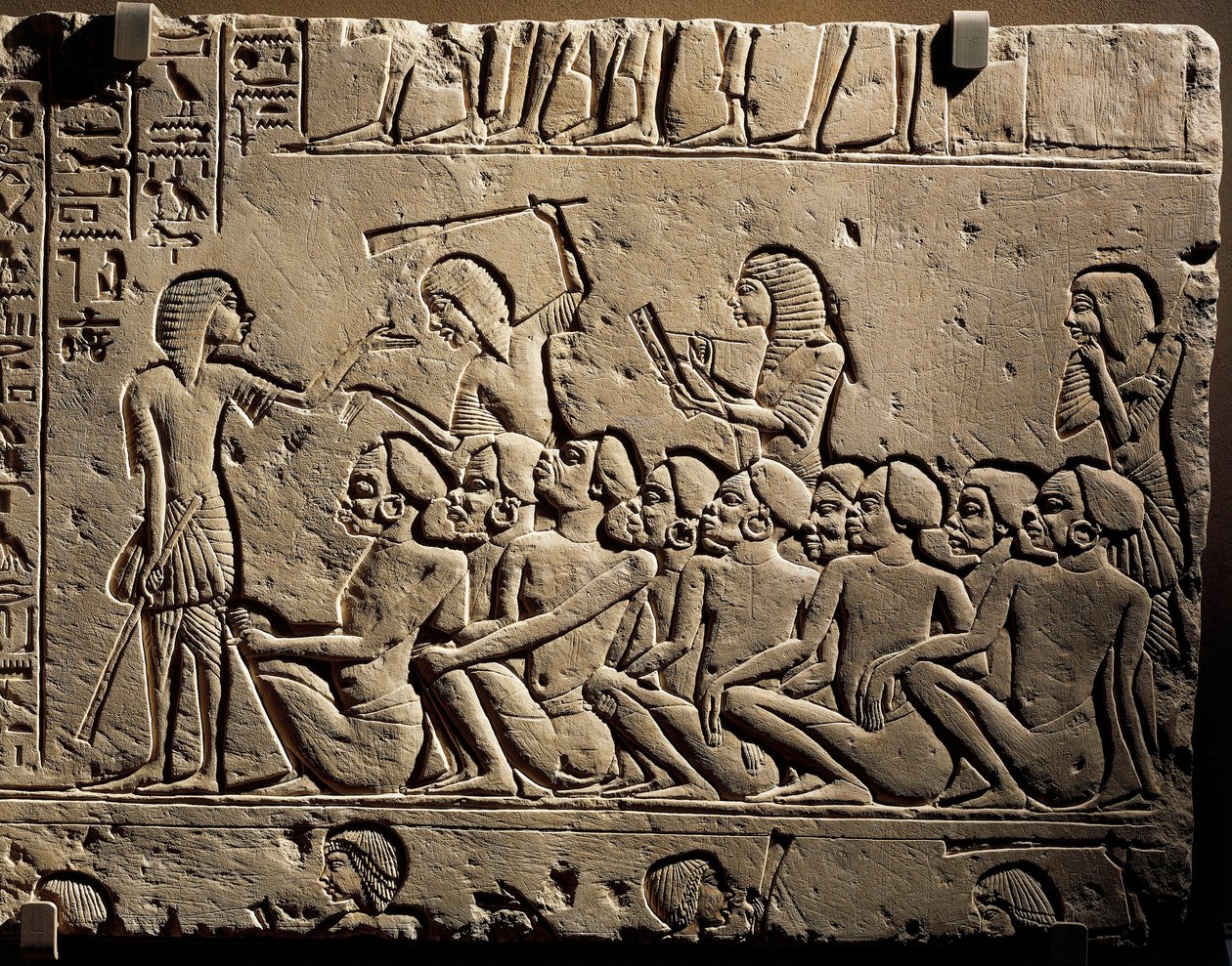 Grupa murzyńskich więźniów otoczona przez strażników uzbrojonych w pałki, podczas gdy skryba sporządza raport, relief z grobowca Horemheba w Sakkarze autorstwa Egyptian 18th Dynasty