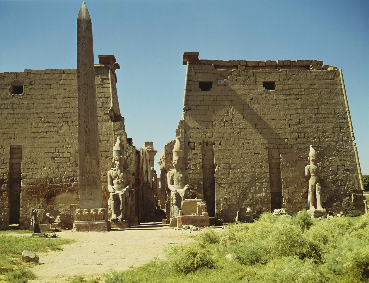 Fasada i Pierwszy Pylon z dwoma siedzącymi posągami Ramzesa II i pozostałym obeliskiem autorstwa Egyptian 19th Dynasty