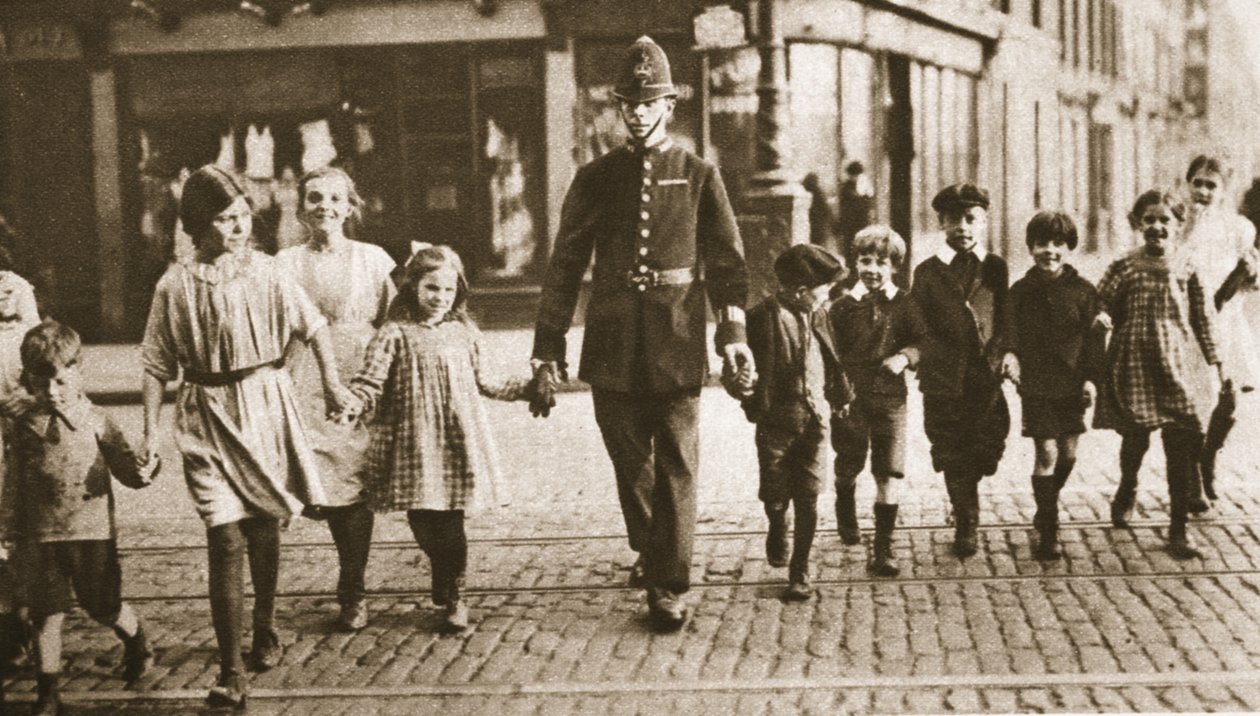 Bobby on the beat pomagający dzieciom przejść przez ulicę pod koniec dnia szkolnego, z Wonderful London, opublikowany w latach 1926-27 (fotograwiura) autorstwa English Photographer