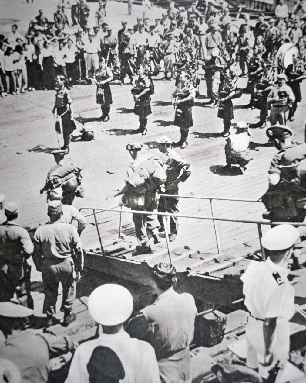 Kilted dudziarzy grają na brzegu z 1. Batalionu Argyll i Sutherland Highlanders z HMS Ceylon w Pusan, 29 sierpnia 1950 (zdjęcie czarno-białe) autorstwa English Photographer