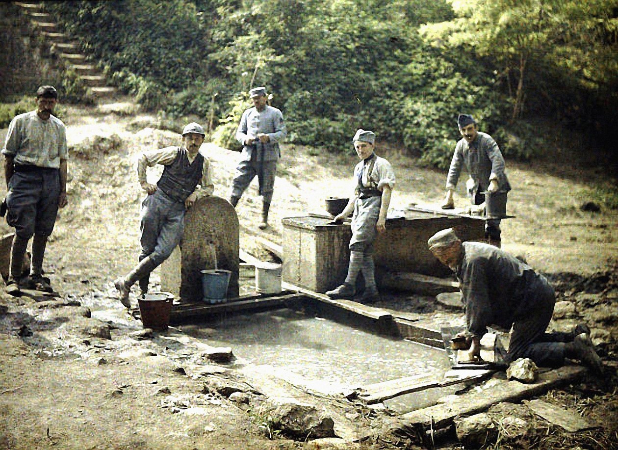 Sześciu francuskich żołnierzy z wiadrami i praniem przy fontannie, Soissons, Aisne, Francja, 1917 (autochrome) autorstwa Fernand Cuville