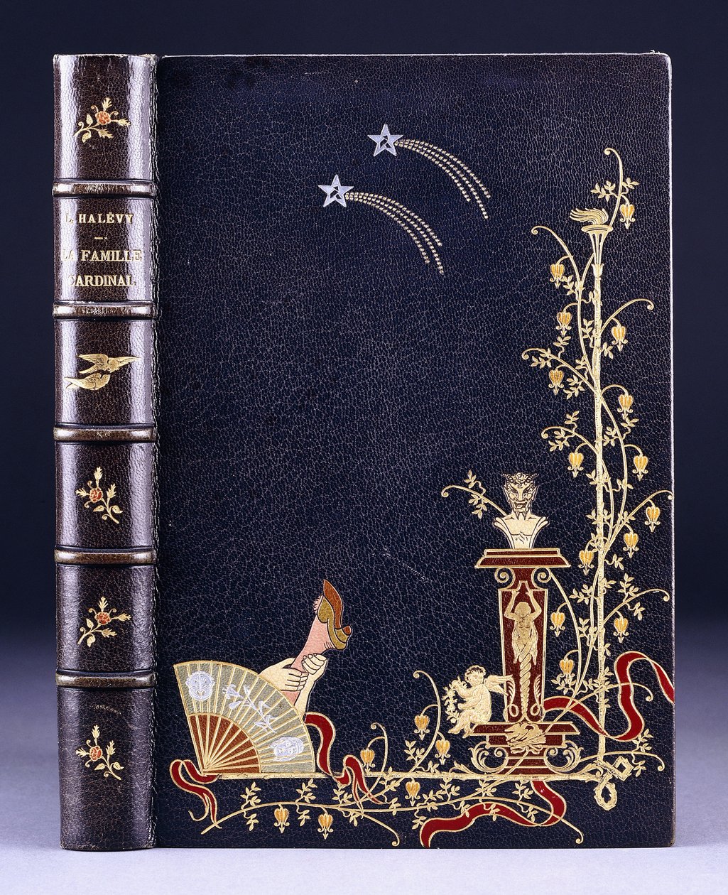 Górna okładka książki z dwiema spadającymi gwiazdami, pochodnią, liśćmi, faunem na postumencie, puttem i nogą za wachlarzem, 1893 autorstwa French School