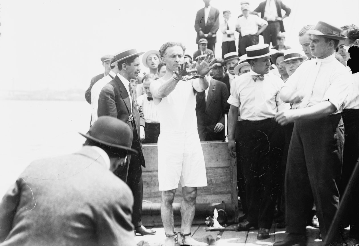 Harry Houdini zostaje zakuty w kajdanki, zanim zostanie przybity do skrzyni i spuszczony do Zatoki Nowojorskiej, 1912 r. autorstwa George Grantham Bain