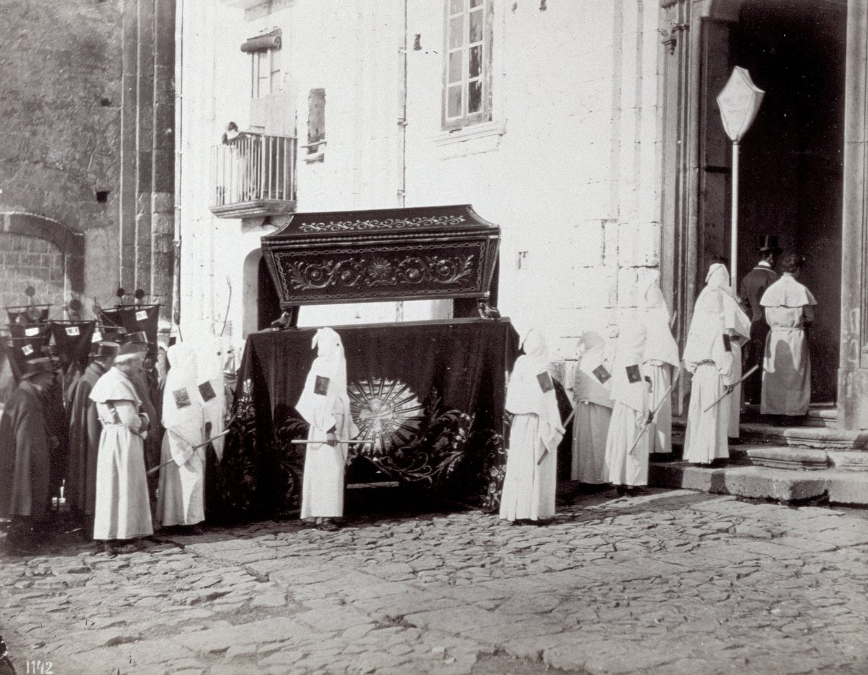 Procesja żałobna Zgromadzenia św. Franciszka w Neapolu. Na pierwszym planie, przed kościołem, liczni „bracia bractwa” w białych tunikach i kapturach towarzyszą katafalkowi ozdobionemu haftowanym płótnem, na którym umieszczona jest trumna autorstwa Giorgio Sommer