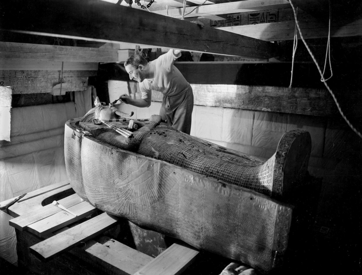 Odkrycie grobowca faraona Tutanchamona w Dolinie Królów (Egipt): w komorze grobowej, Howard Carter pracuje nad pokrywą drugiej trumny, październik 1925, fot. Harry Burton (p1568) autorstwa Harry Burton