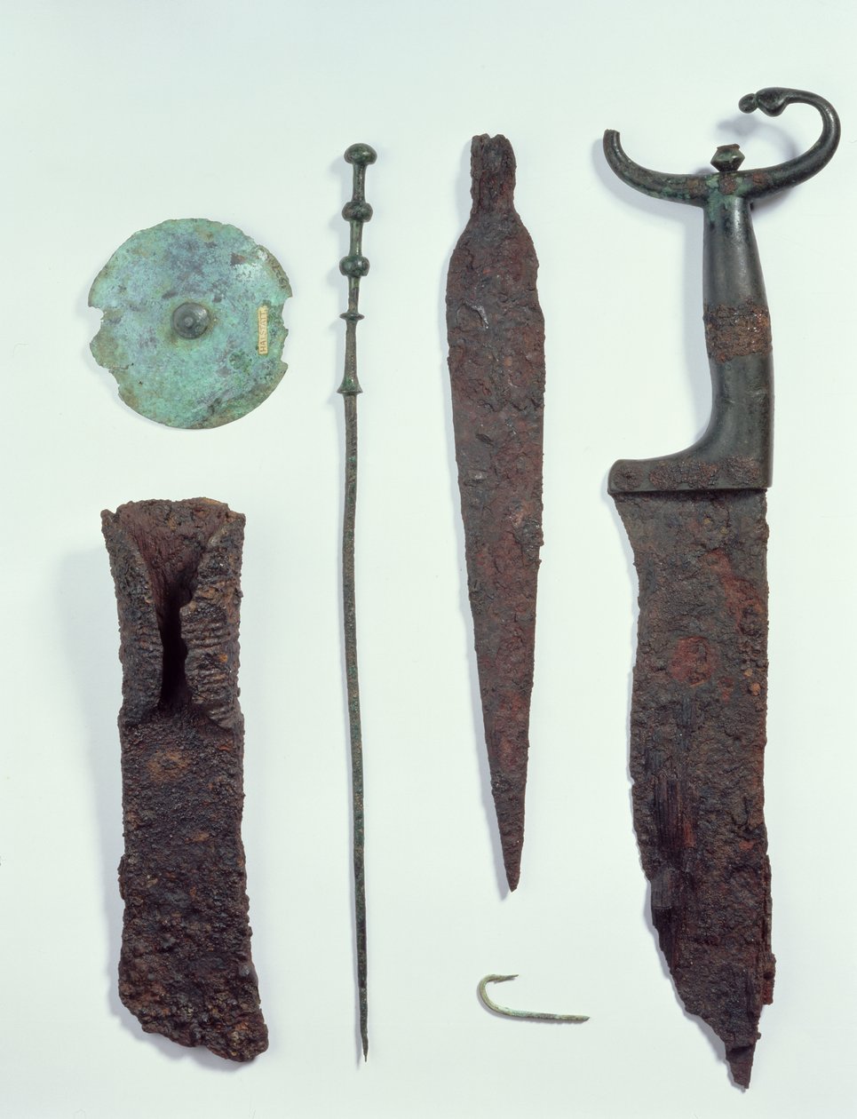 Od góry do dołu: nóż, grot, haczyk na ryby, szpilka do ubrania, dysk do paska i topór, wszystkie znalezione w męskich grobach w Hallstatt, epoka żelaza autorstwa Iron Age