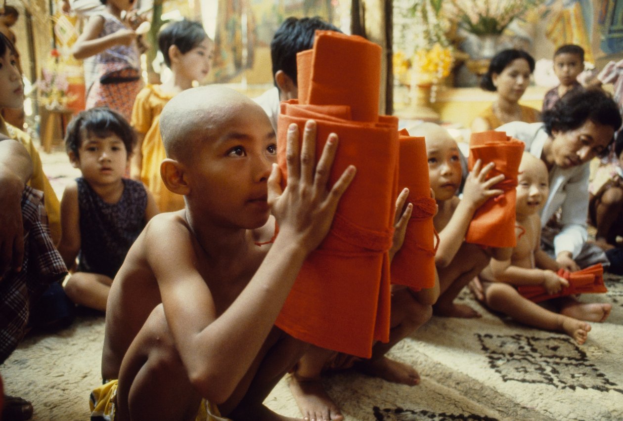 Młody chłopiec z ogoloną głową otrzymuje strój mnicha. Mandalay, Birma. autorstwa James L Stanfield