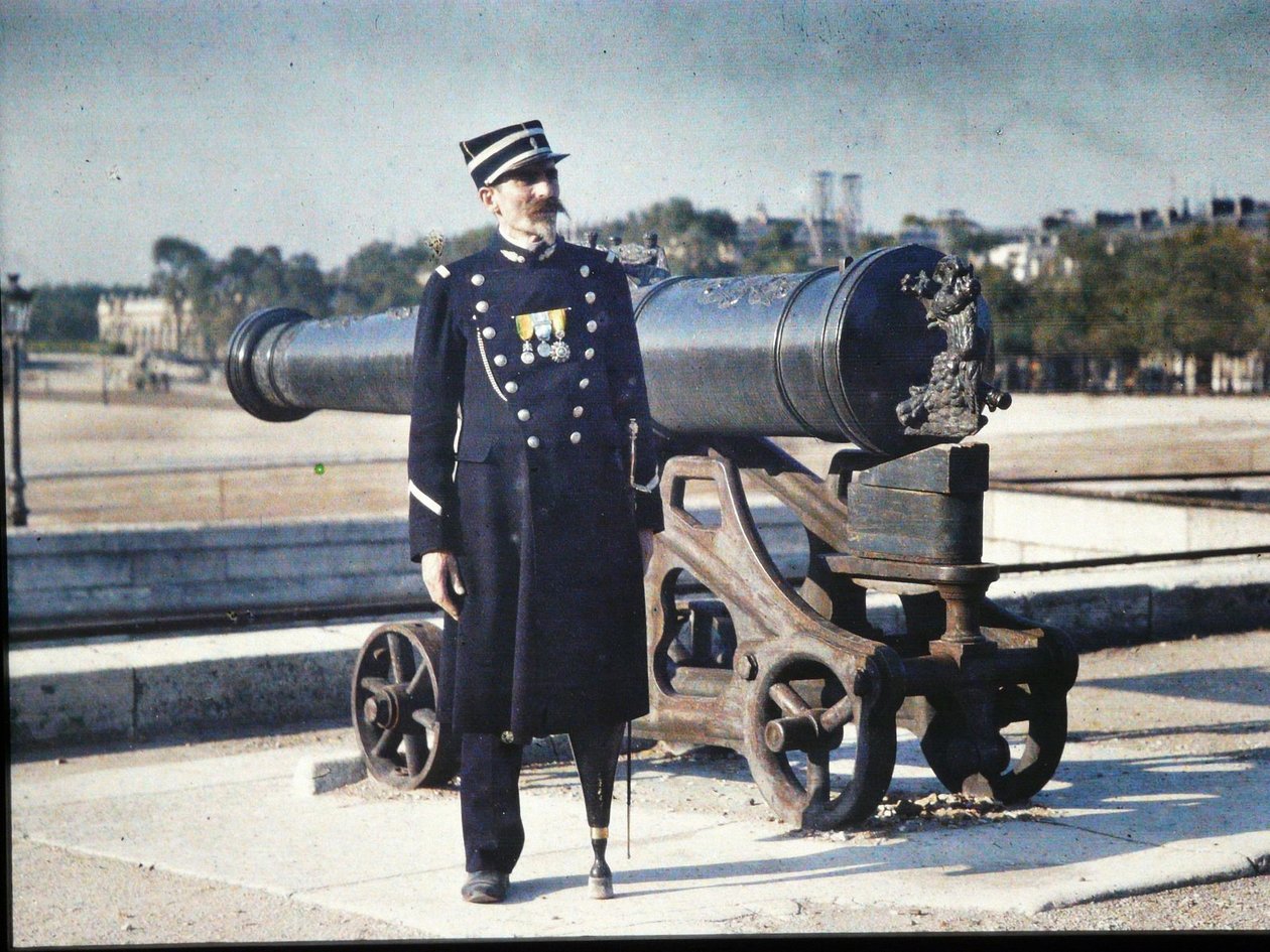 Żołnierz w mundurze z trzema medalami stoi obok armaty w Paryżu, 1918 (autochrom) autorstwa Jules Gervais Courtellemont