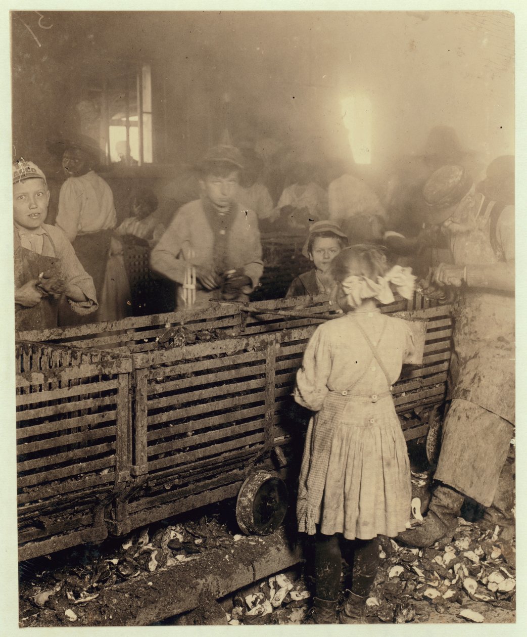 Fabryka Lowden Canning Company, Bluffton w Południowej Karolinie, pokazująca siedmioletnią dziewczynkę, która ze swoim sześcioletnim bratem i jedenastoletnim chłopcem, który robi 6 naczyń, wyrzuca dziennie 3 doniczki ostryg, 1913 (mc p autorstwa Lewis Wickes Hine