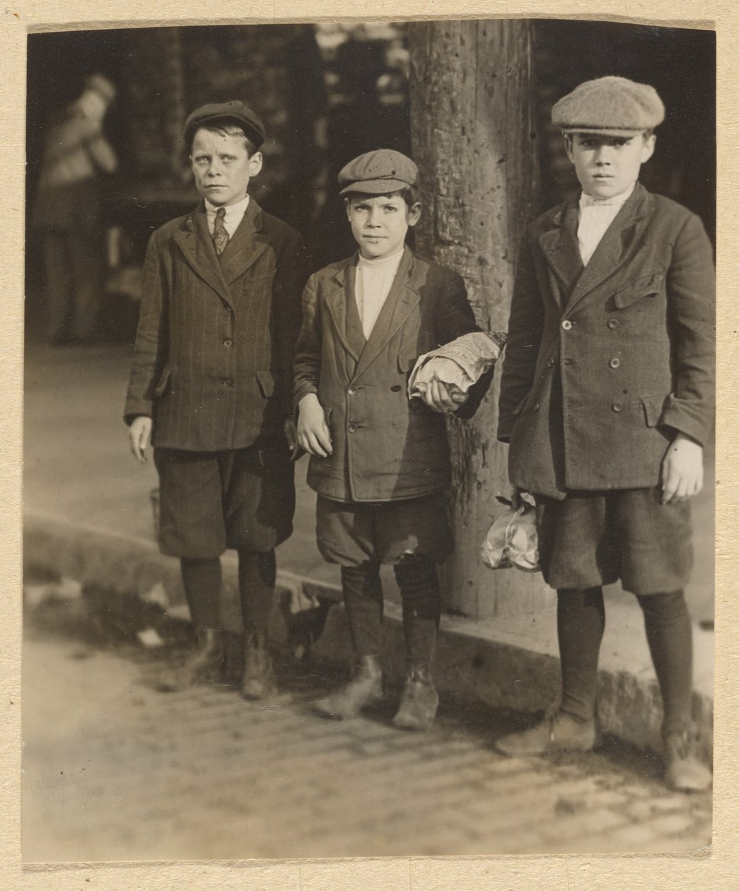 [Trzech chłopców na ulicy miasta w spodenkach i czapkach]. autorstwa Lewis W. Hine