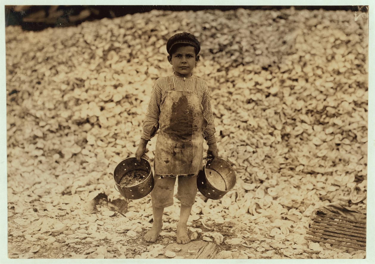 5-letni migrant zbieracz krewetek Manuel przed stosem muszli ostryg, pracujący przez drugi rok w Dunbar, Lopez, Dukate Company, Biloxi, Mississippi, 1911 autorstwa Lewis Wickes Hine
