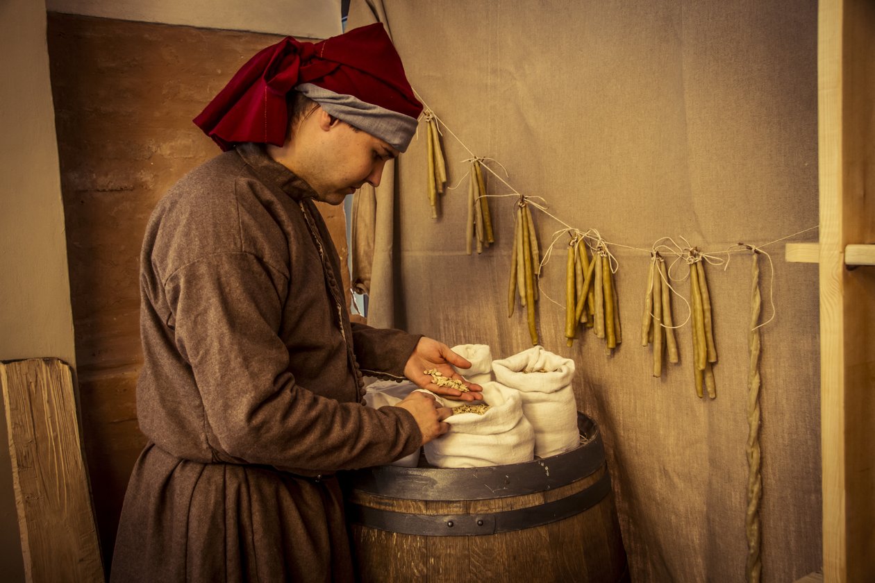Rekonstrukcja historyczna: Świece i worki pszenicy, żyta i jęczmienia w aptece Diotaiuti, Imola, Włochy, połowa XIV w. (foto) autorstwa Unbekannt Unbekannt