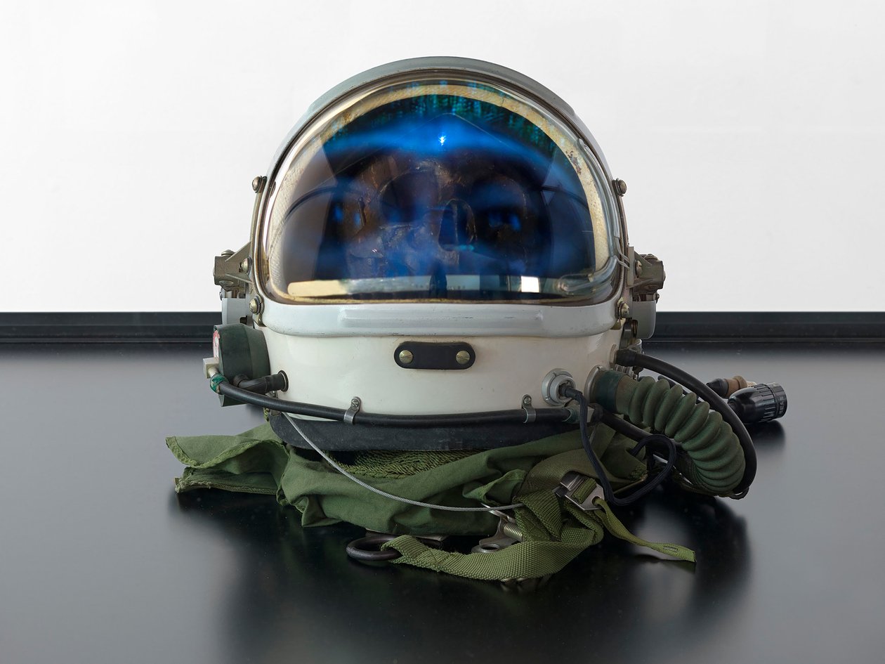 Alpha Omega, 2016 (szkło, ekran LCD, odtwarzacz multimedialny, replika czaszki, hełm kosmiczny, drewno) autorstwa Mat Collishaw