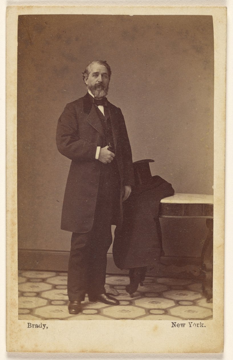[Nieznany brodaty mężczyzna stojący, a na stoliku obok leżą cylinder i płaszcz] autorstwa Mathew B. Brady