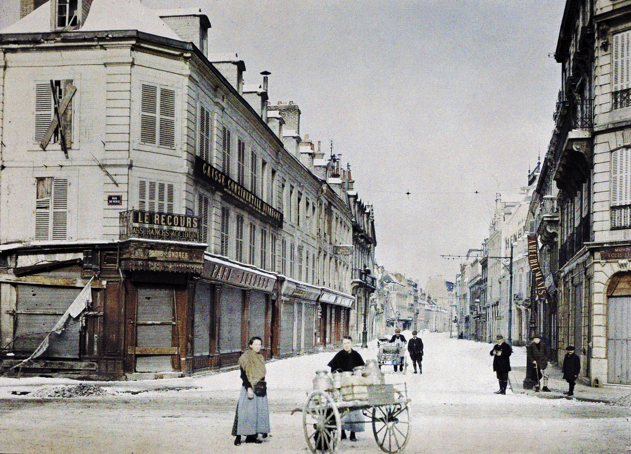 Kobieta z wózkiem wypełnionym bańkami mleka na Rue de Vesle i mężczyzna z innym wózkiem na Rue de Talleyrand za nią, Reims, Francja, 3 marca 1917 (autochrome) autorstwa Paul Castelnau
