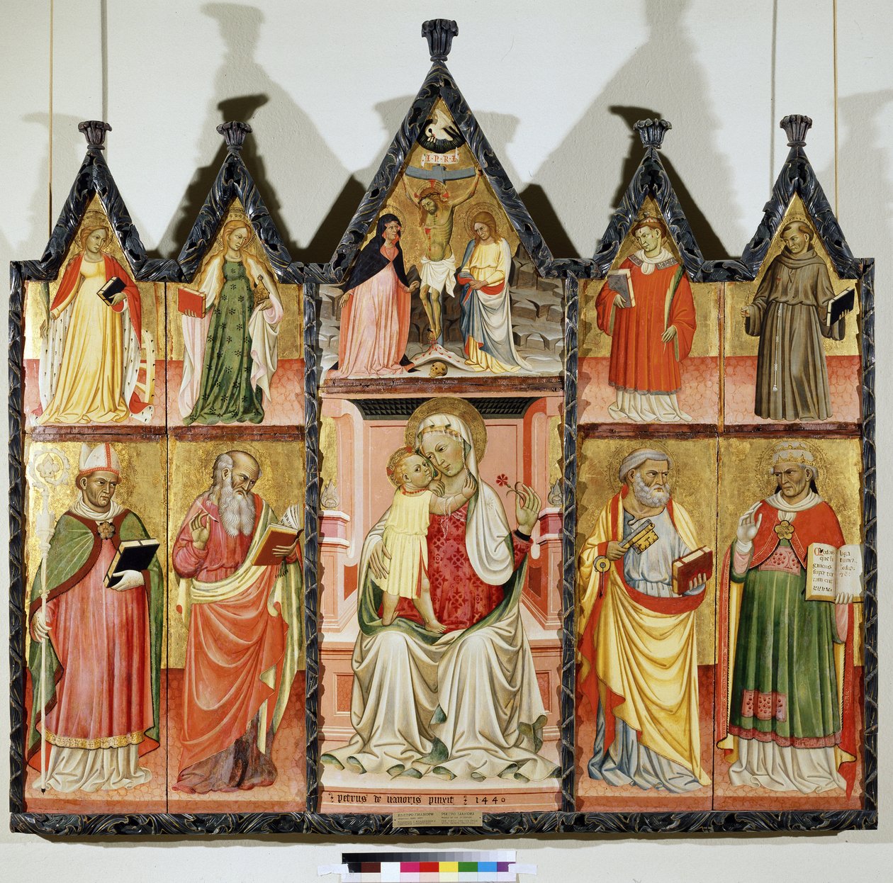 Poliptyk Matki Boskiej z Dzieciątkiem i Świętymi. U góry po lewej: Święta Katarzyna Aleksandryjska i Święta Maria Magdalena. W centrum wokół Chrystusa na krzyżu z napisem „INRI”” (I.N.R.I.). Maryi Panny i św. Jana. U góry po prawej: S autorstwa Pietro di Giovanni Lianori