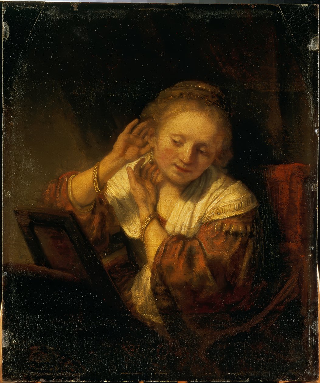 Młoda kobieta ozdabiająca się kolczykami autorstwa Rembrandt van Rijn