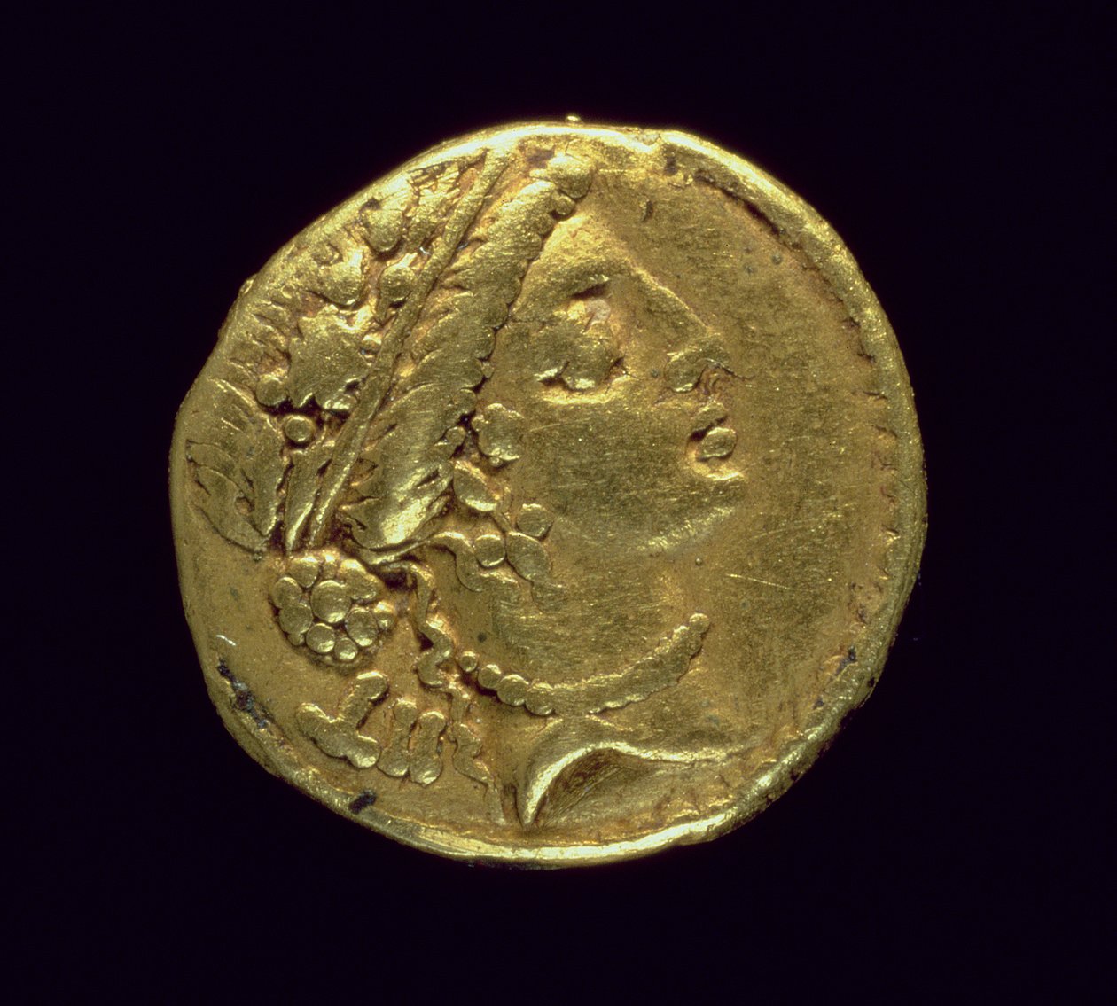 Aureus (awers) wybity przez Juliusza Cezara (110-44 p.n.e.) przedstawiający kobiecą głowę po prawej stronie ubraną w wieniec dębowy i diadem (złoto) autorstwa Roman