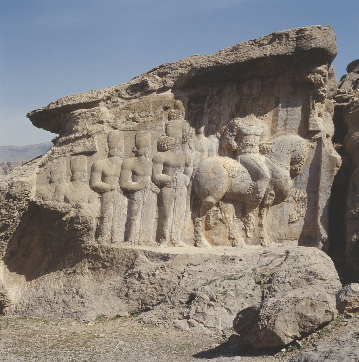 Relief naskalny przedstawiający Szapura I (AD 241-72) i jego rodzinę noszących herby na kapeluszach, z trójjęzycznym napisem na koniu w języku greckim, partyjskim i środkowoperskim autorstwa Sasanian