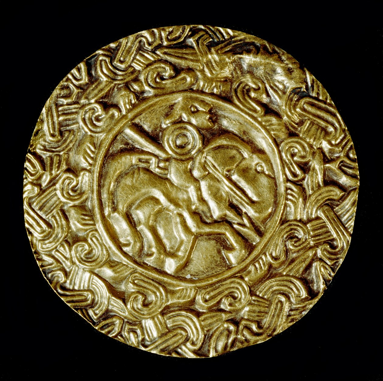 Archeologia średniowiecza (średniowiecze). Sztuka barbarzyńska Lombardii: złoty dysk. W centrum znajduje się święty na koniu z włócznią i wokół motywów zwierzęcych. Sztuka lombardzka, ok. 600. Wymiary: 47 cm Włochy, Cividale del Friuli, Muzeum Archeologicz autorstwa School Lombard
