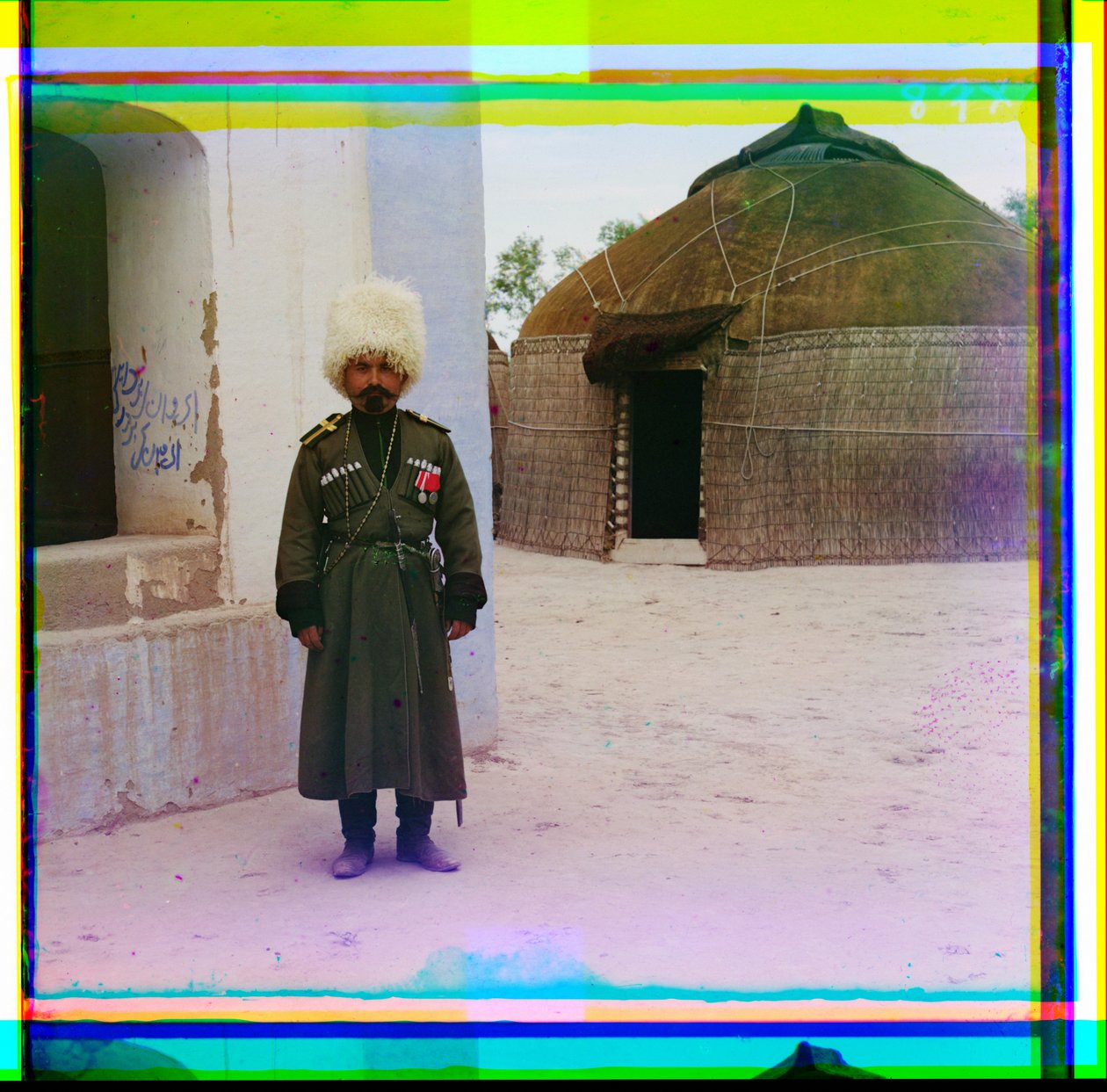 Uzbrojony mężczyzna w mundurze stoi obok budynku z jurtą w tle, Rosja, 1915 autorstwa Sergey Prokudin Gorsky