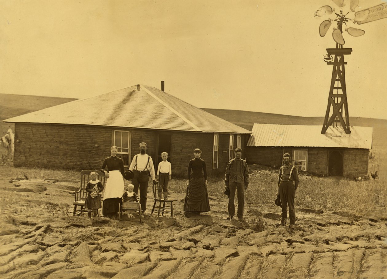Rodzina osadników przed domem darniowym z wiatrakiem na dachu sąsiedniego budynku w hrabstwie Custer w stanie Nebraska, ok. 1885 r. (zdjęcie czarno-białe) autorstwa Solomon D. Butcher