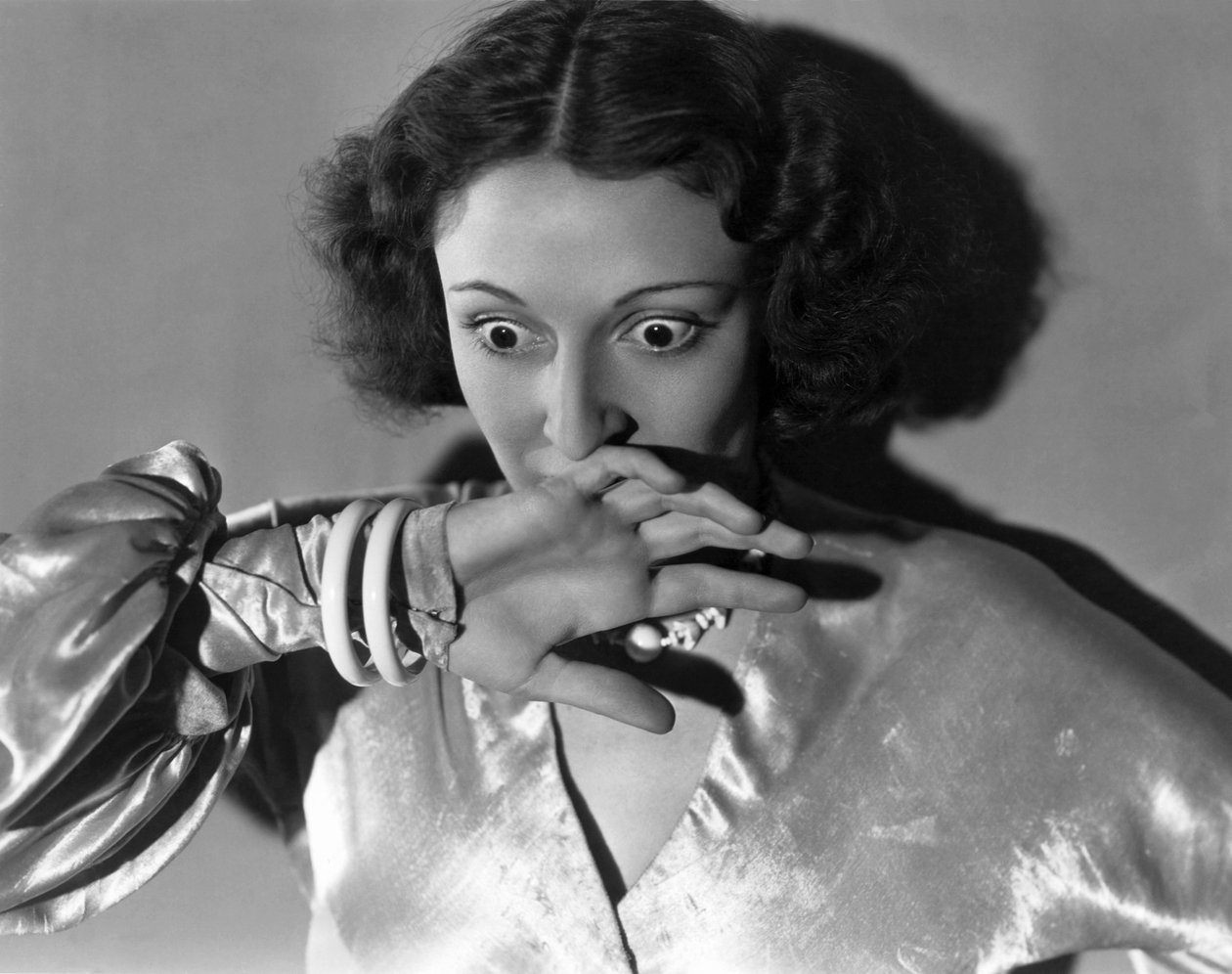 Hollywood, Kalifornia: c.1932 Zbliżenie młodej kobiety zakrywającej usta ze strachu. (zdjęcie czarno-białe) autorstwa Unbekannt