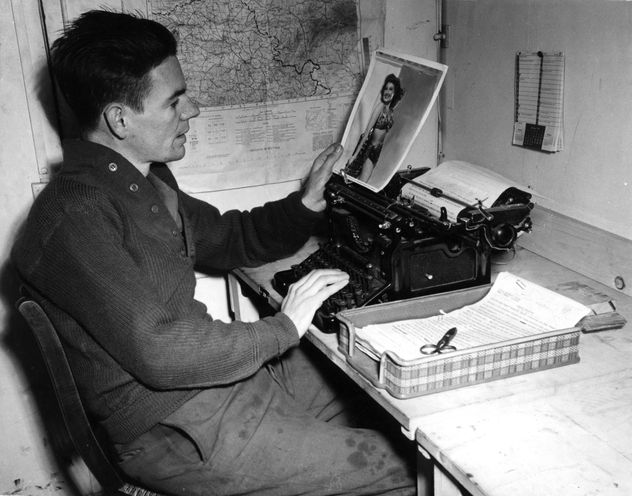 Druga wojna światowa (1939-1945) – II wojna światowa (II lub II wojna światowa): Mutzig (Alzacja) Francja 1 grudnia 1944: kapral Flanerty kronikarz z Beachead News (dziennika wiadomości GI) patrzy na pin-upowe zdjęcie, które publikuje w kolejny numer gazet autorstwa Unbekannt