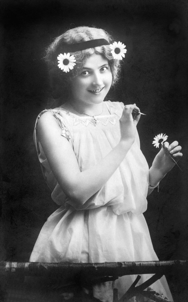 Kobieta wyciągająca płatki z kwiatka: „” On mnie kocha. On mnie nie lubi. On mnie kocha…” Fotografia około 1912 r. autorstwa Unbekannt