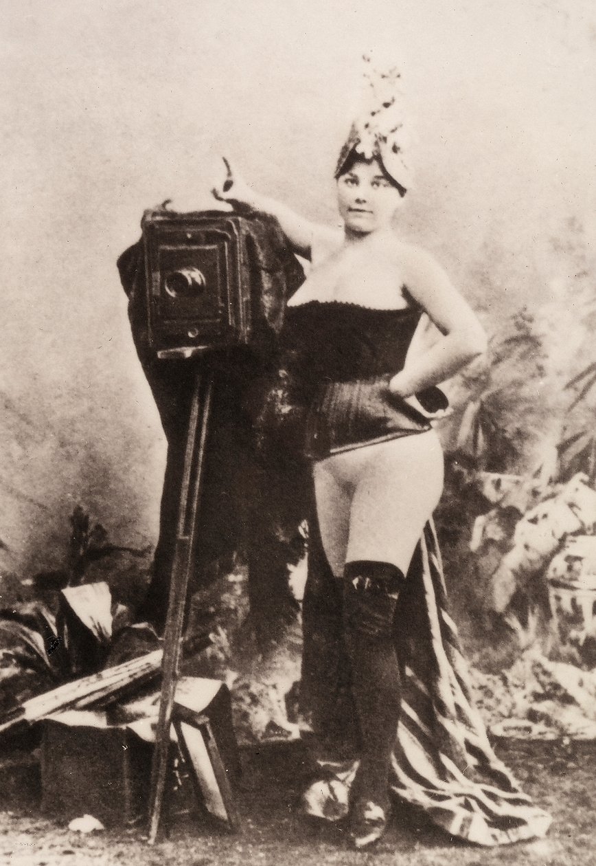 Portret częściowo nagiej kobiety opierającej się o zabytkowy aparat. autorstwa Unknown photographer
