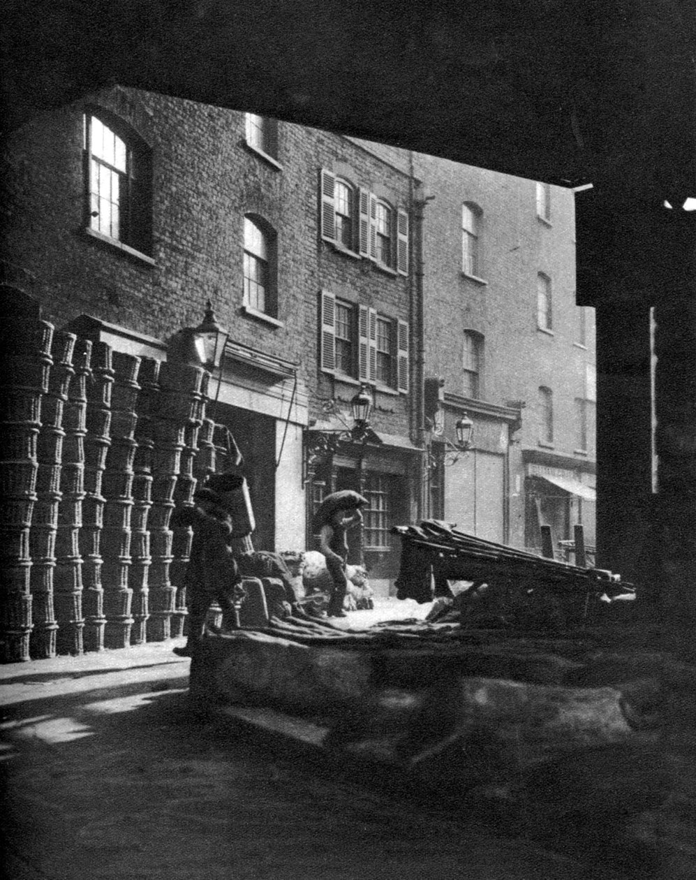 Kosze z owocami ułożone w stosy przy domach na Borough Market, Londyn, 1926-1927. autorstwa Whiffin