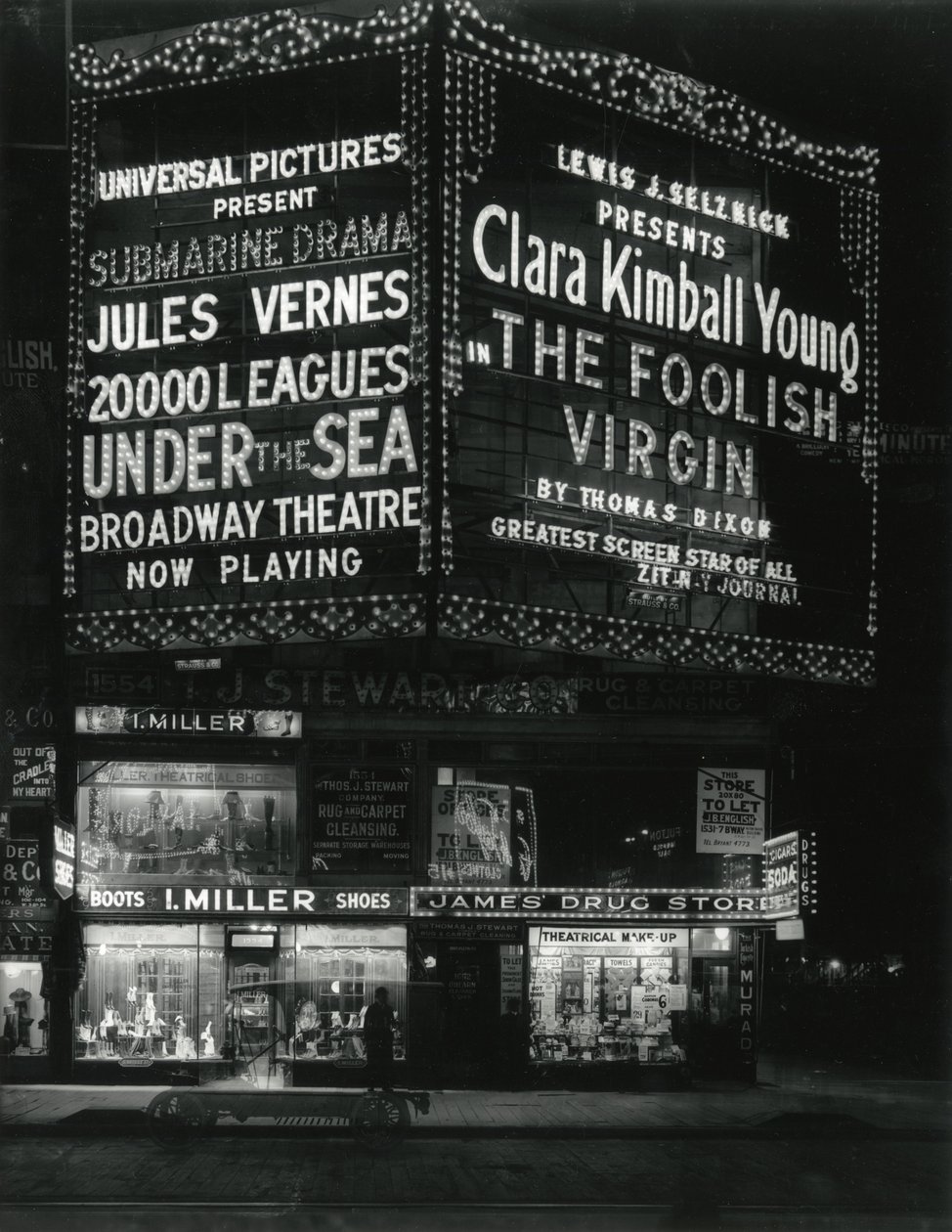 1554 Broadway przy 46th Street, I. Miller Shoes; James Drug Store i duże namioty do filmów oświetlone powyżej. autorstwa William Davis Hassler
