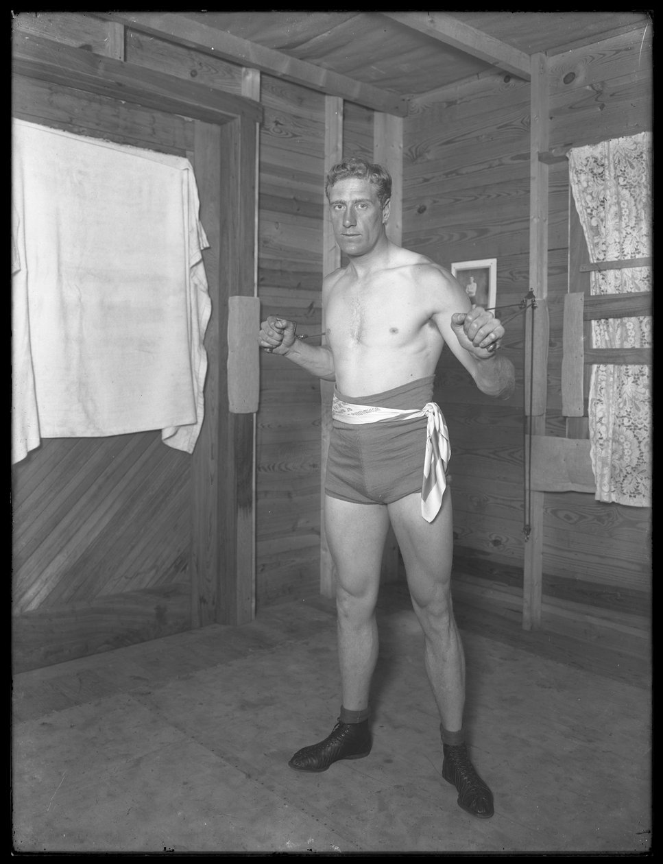 Angielski bokser William Thomas Wells (Bombardier Billy Wells), pozuje w strojach treningowych z ciężarkami, ok. 1911 r. autorstwa William Davis Hassler