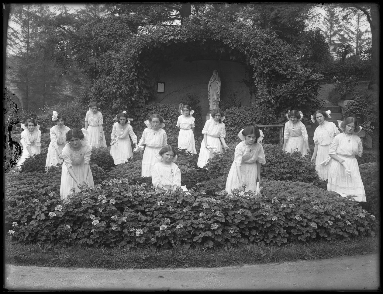 Klasa maturalna dziewcząt z rzymskokatolickiego azylu dla sierot w ogrodzie kwiatowym, przed grotą Marii Panny, fot. 1912 bw autorstwa William Davis Hassler