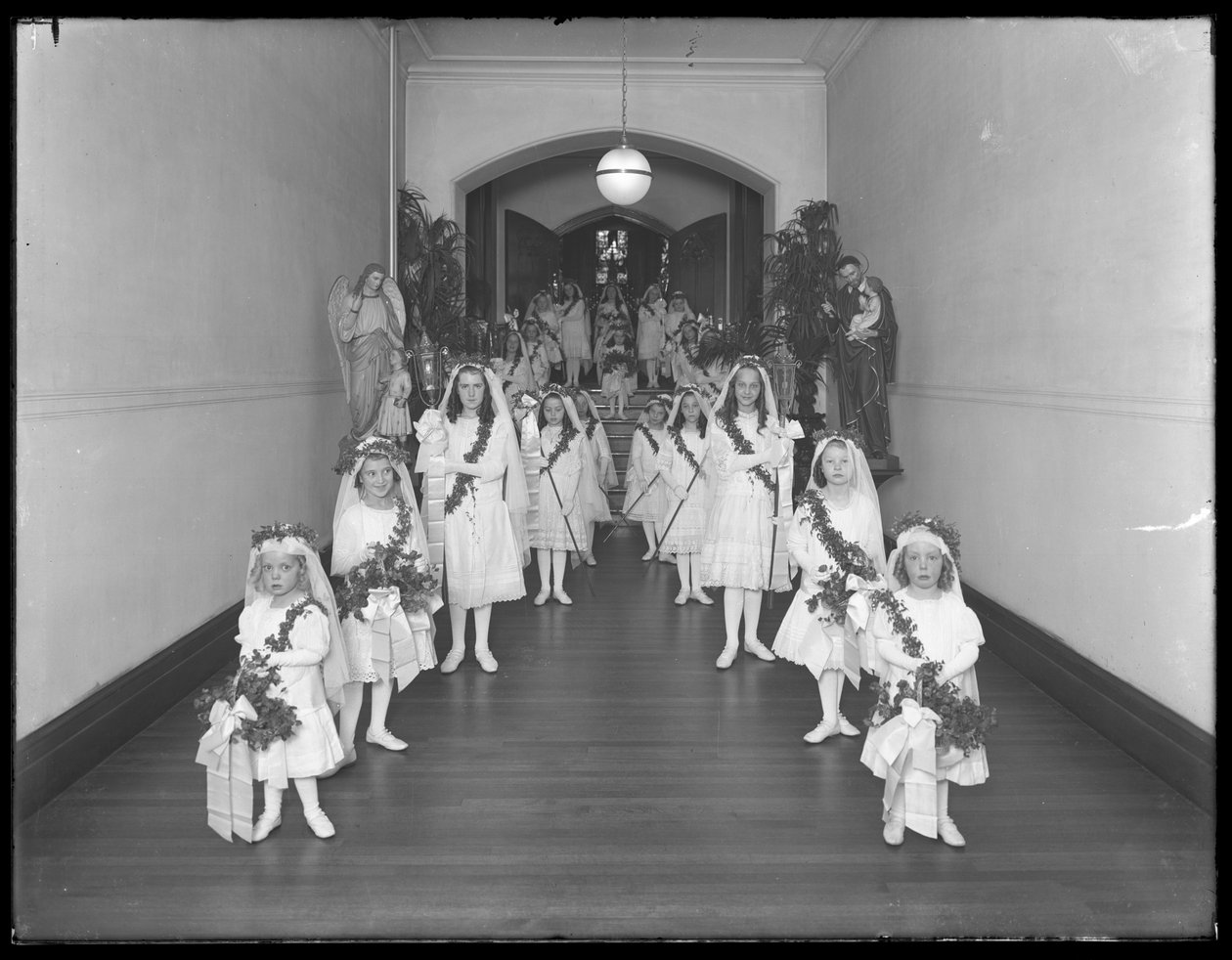 Dziewczynki w rzymskokatolickim azylu dla sierot w Kingsbridge, Bronx, wracają z kaplicy w białych sukniach z wieńcami i wieńcami, 20 października 1914 autorstwa William Davis Hassler