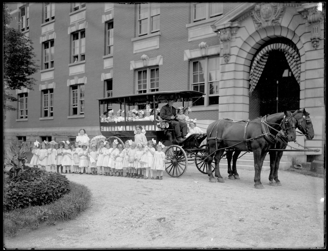 Małe dziewczynki pozują przed i przed wozem konnym, przed niezidentyfikowanym budynkiem, prawdopodobnie rzymskokatolickim azylem dla sierot, Kingsbridge, Bronx, ok. 1910 autorstwa William Davis Hassler